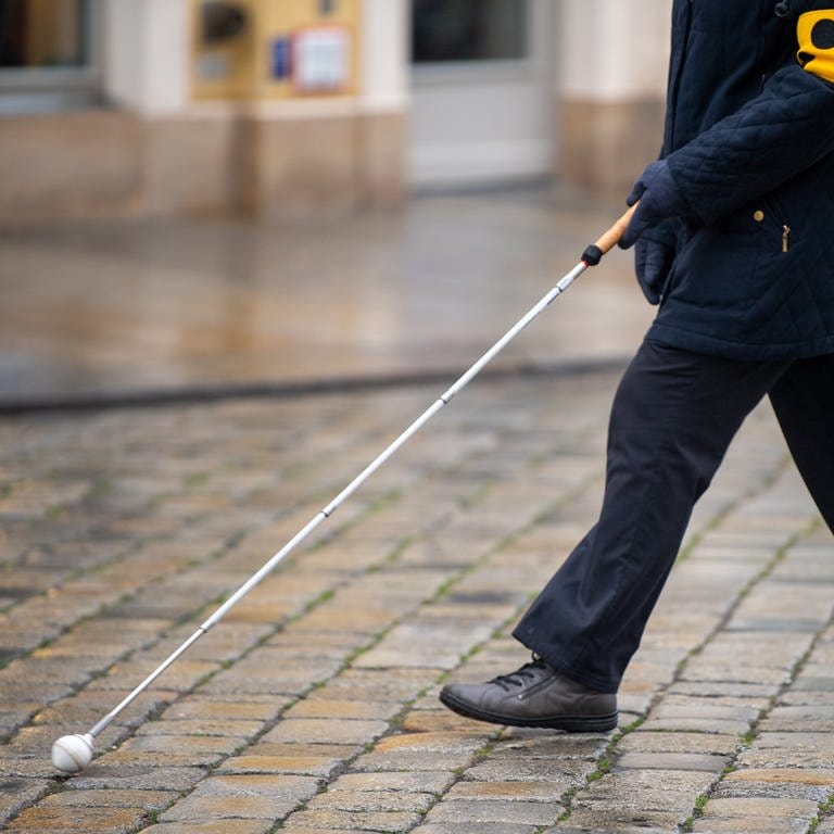 Eine blinde Person geht mit ihrem Blindenstock eine Straße entlang. (Foto: dpa Bildfunk, Picture Alliance)