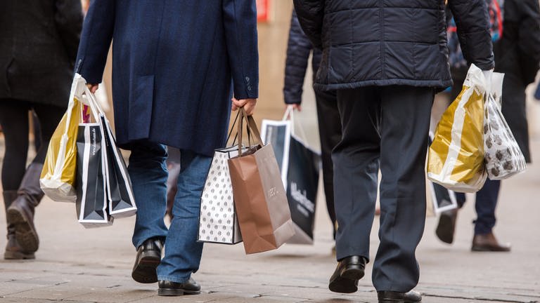 Zwei Männer gehen mit zahlreichen Tüten durch eine Einkaufsstraße in einer Innenstadt. (Foto: picture-alliance / Reportdienste, Daniel Bockwoldt)