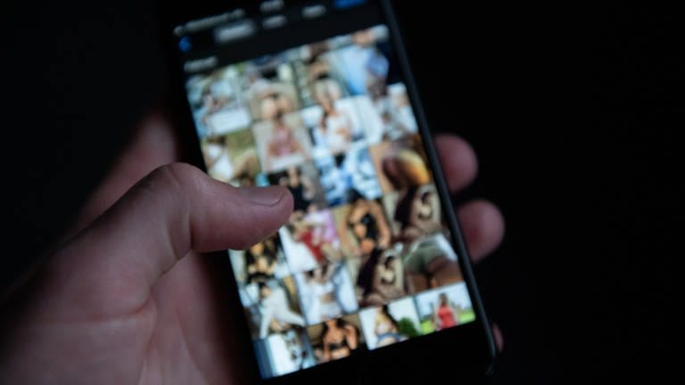 Auf einem Smartphone sind pornografische Bilder zu sehen. (Symbolbild)