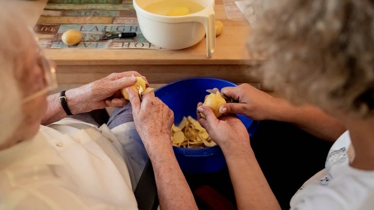 Eine Angehörige versucht den Alltag mit einem Demenzkranken zu meistern. Hier schälen sie gemeinsam Kartoffeln. (Foto: picture-alliance / Reportdienste, Christoph Söder)