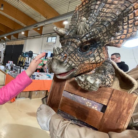 Proud Nerd Convention in Trier. Die kleine "Mandalorianerin" bestaunt einen Baby-Dino aus Jurassic Park.  (Foto: SWR, Lara Bousch)