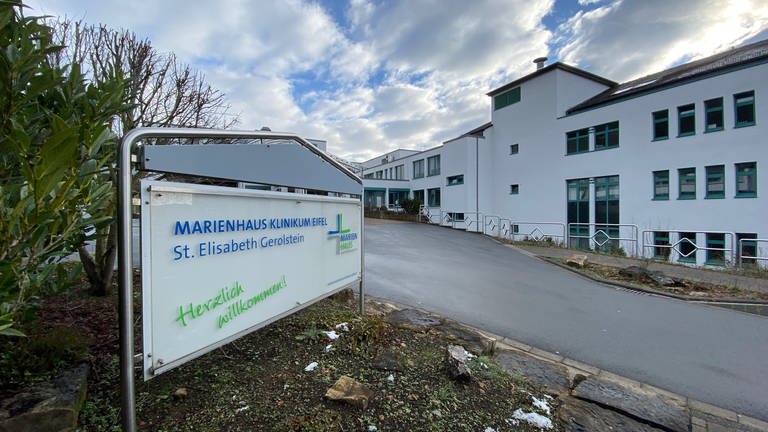 Hinter dem Schild "Marienhaus Klinikum Eifel - St. Elisabeth Gerolstein" ist im Hintergrund das Gerolsteiner Krankenhausgebäude zu sehen. (Foto: SWR, Anna-Carina Blessmann)