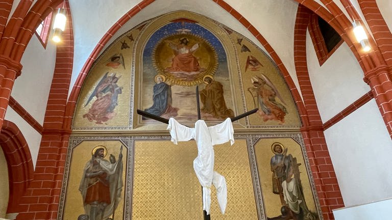 St. Gangolf Trier: Vor dem großen Wandfresko von Lasinsky aus dem 19. Jahrhundert hängt eine mit weißem Tuch verhüllte Stoffplastik, die Christus am Kreuz darstellt (Foto: SWR, Nicole Mertes)