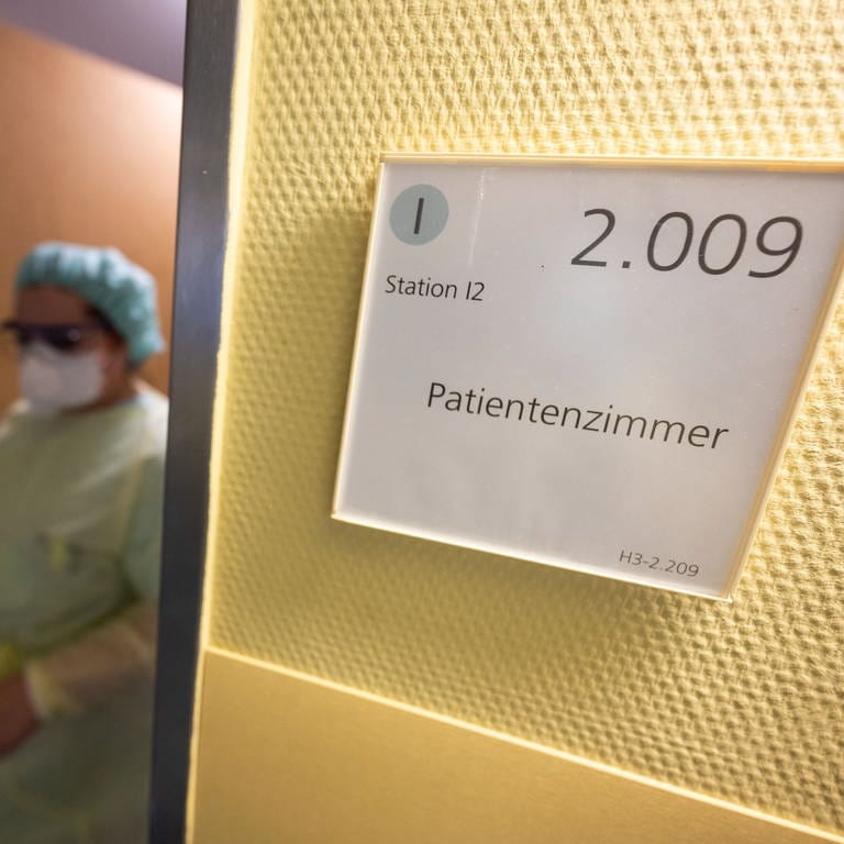 Eine Krankenpflegerin verlässt in Schutzkleidung ein Patientenzimmer. Es ist ein neues Phänomen: Die Corona-Pandemie verlagert sich stärker auf die Normalstationen der Krankenhäuser.  (Foto: picture-alliance / Reportdienste, picture alliance/dpa / Marijan Murat)