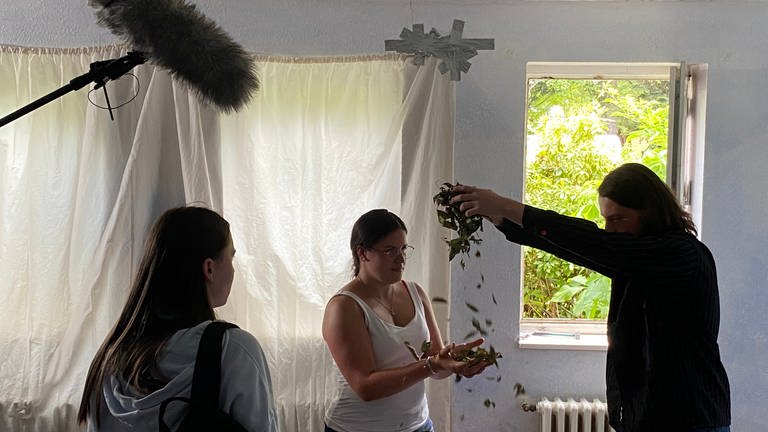 Für eine Traumsequenz lässt Regisseur und Autor Simon (rechts) vertrocknete Blätter in die Hände von Hauptdarstellerin Roxane (Mitte) fallen. (Foto: SWR, Anna-Carina Blessmann)
