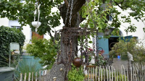 Alte Schlüssel hängen an einem Kuchenrost unter dem Pfirsischbaum. Die Konder-Michelots sammeln gerne alte Dinge, um sie im Garten auszustellen. (Foto: SWR, Lara Bousch)