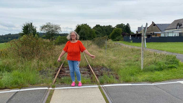 Andrea Horst kann gefahrlos auf den Zuggleisen stehen, denn durch Höchstberg in der Eifel ist schon seit über zehn Jahren kein Zug mehr gefahren. (Foto: SWR, Anna-Carina Blessmann)