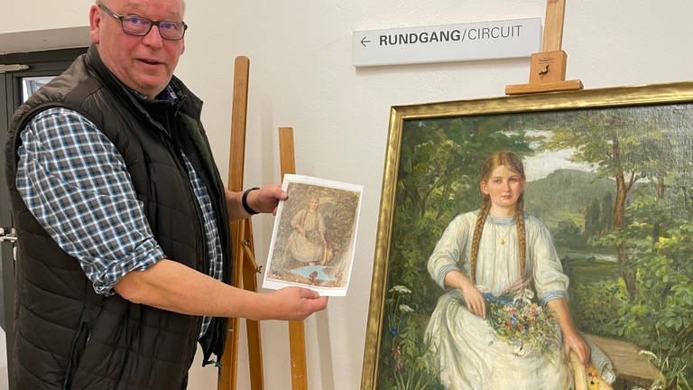 Michael Schwinge vom Verein "wir-einander e.V." zeigt, in welchem Zustand dieses Gemälde eines Mädchens nach der Flut im Ahrtal war. 