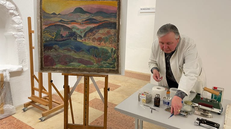 Dimitri Scher erklärt, wie er für die Restautierung des Gemäldes aus dem Ahrtal in Trier Schritt für Schritt vorgegangen ist. (Foto: SWR, Dunja v. Morzé)