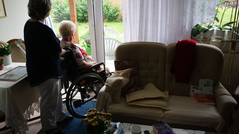 Pflegekraft mit Seniorin im Rollstuhl (Foto: picture-alliance / Reportdienste, Peter Steffen)