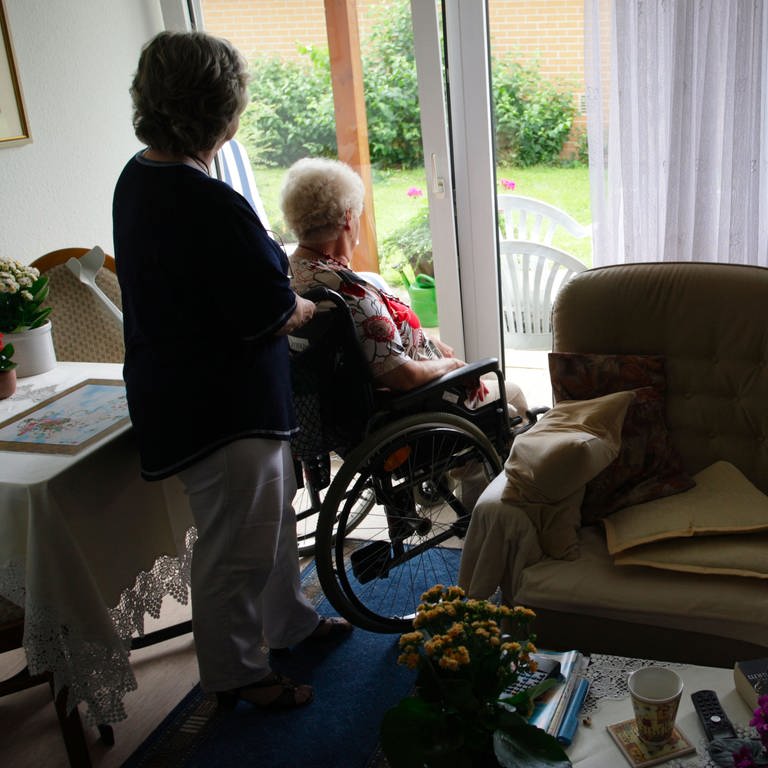 Pflegekraft mit Seniorin im Rollstuhl (Foto: picture-alliance / Reportdienste, Peter Steffen)