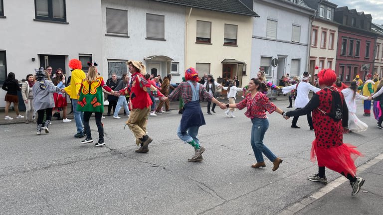 Schärensprung Trier-Biewer: Narren in unterschiedlichen Kostümen hüpfen in Schlangenlinien durch die Straßen. 