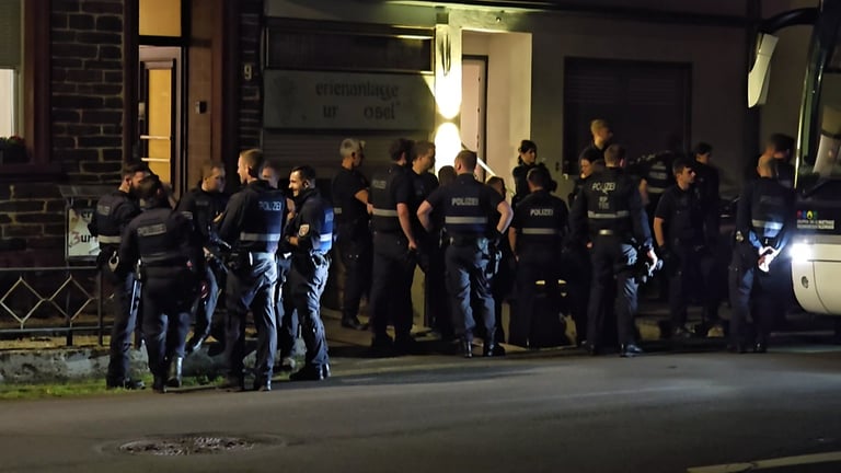 Eine Gruppe von Polizeibeamten steht vor einem Ferienhaus in Kröv an der Mosel. Dort lief ein Einsatz wegen des Verdachts der Verwendung verfassungsfeindlicher Parolen.