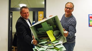 Zwei Wahlhelfer leeren die Urne mit den Stimmzetteln. (Foto: imago images, Marc Schüler)