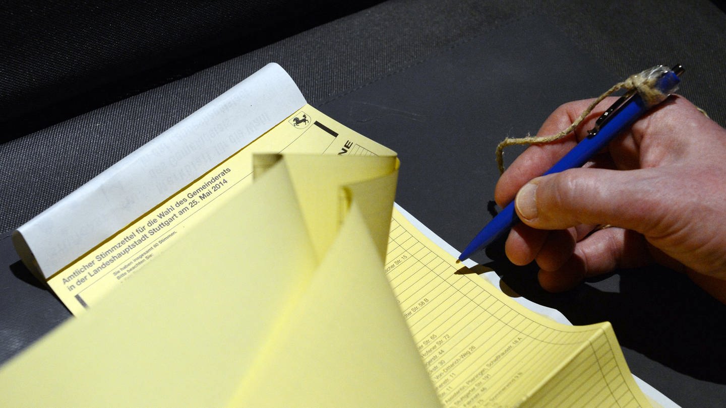 Wahlunterlagen zur Kommunalwahl werden in einer Wahlkabine durchgeblättert.