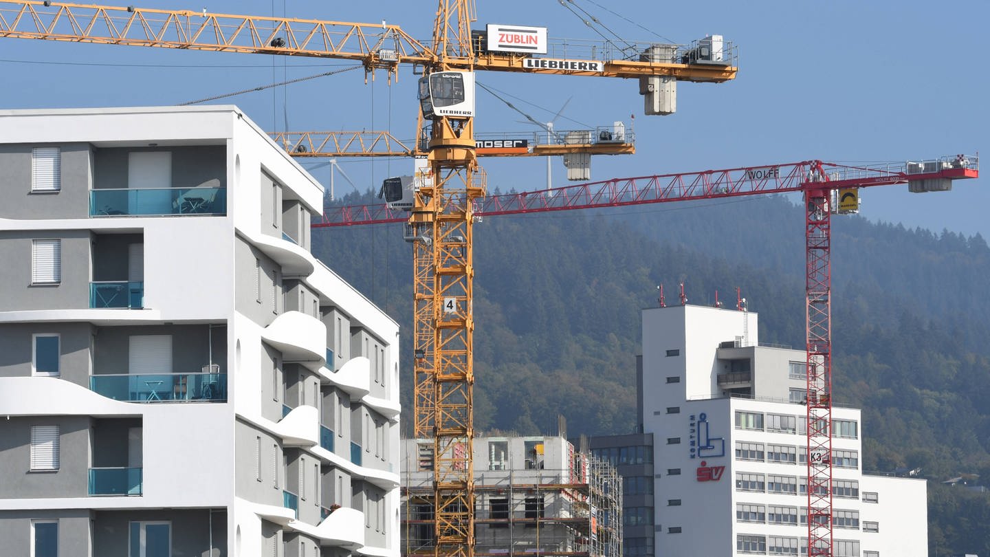 Baukräne ragen in den Himmel in einem Neubauviertel in Freiburg.