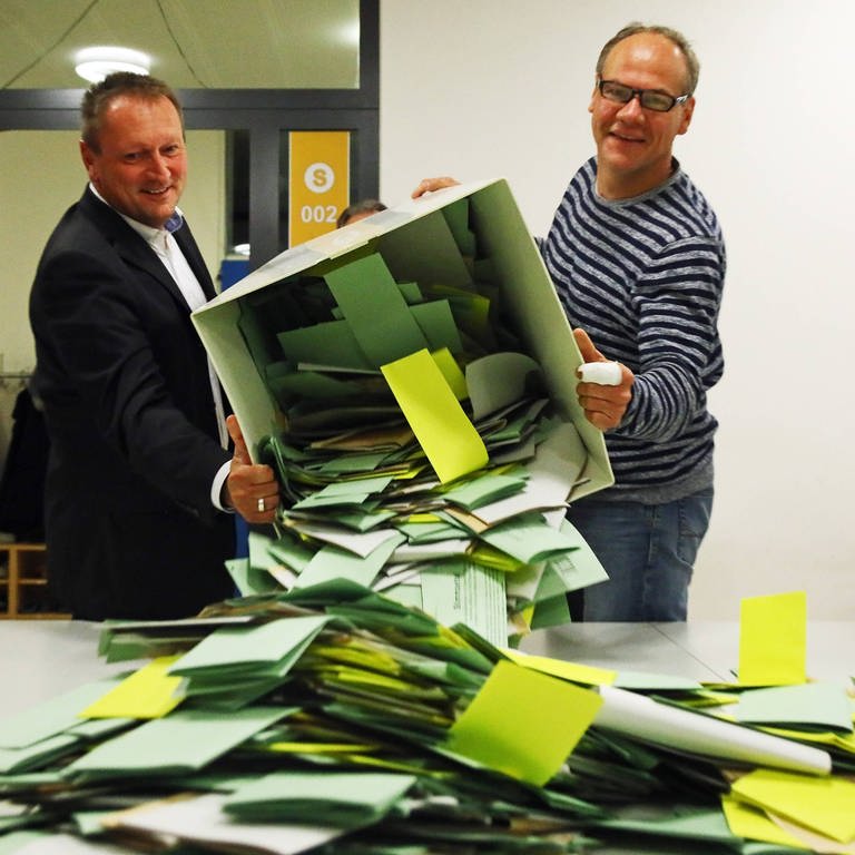 Zwei Wahlhelfer leeren die Urne mit den Stimmzetteln.