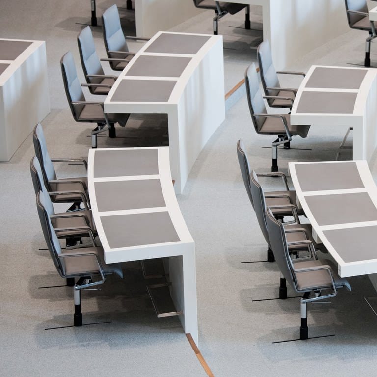 Die leeren Stühle der Abgeordneten in einem Plenarsaal.