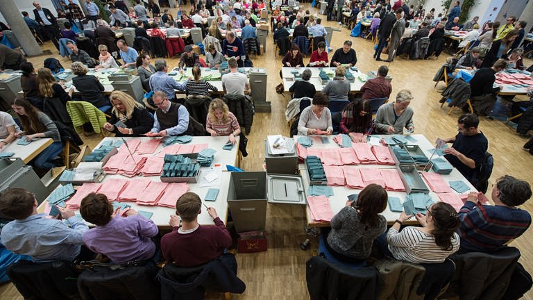 Ehrenamtliche Wahlhelfer beteiligen sich an der Stimmauszählung der Briefwahl für die Wahlkreise in Stuttgart.