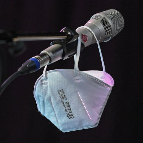 Eine FFP2-Maske hängt an einem Mikrofon (Foto: picture-alliance / Reportdienste, Patrick Pleul)