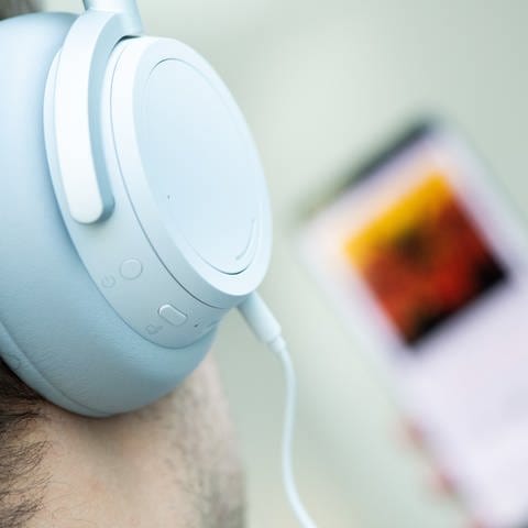 Ein junger Mann hört mit Kopfhörern Musik von seinem Smartphone.