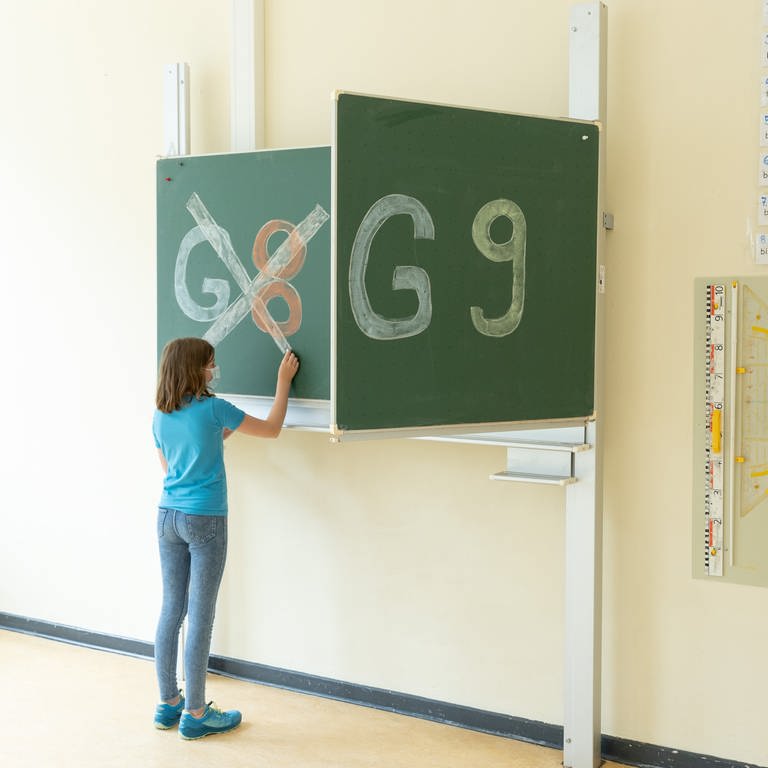 Eine Schülerin einer Schule hat «G8» an einer Tafel durchgestrichen, «G9» daneben bleibt unberührt