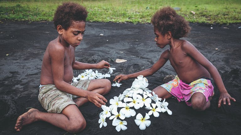 Ambrym, Vanuatu – In Vanuatu bauen die Kinder keine Sandburgen, sondern Sandvulkane. Dieser hier wird mit Frangipani-Blüten dekoriert, damit die Vulkangeister es schön haben und keinen sauren Regen schicken, der die Ernte zerstören könnte. (Foto: Pressestelle, © Ulla Lohmann/Knesebeck Verlag )