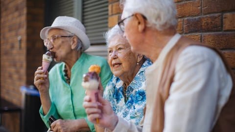 Drei ältere Menschen essen gemeinsam Eis