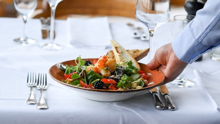 Ein Salatteller wird in einem Restaurant serviert - Personalmangel im Gastgewerbe
