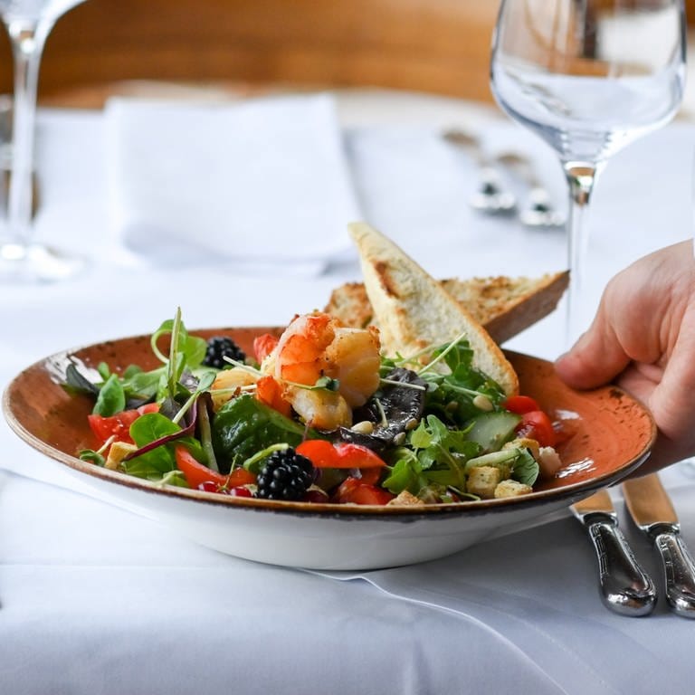 Ein Salatteller wird in einem Restaurant serviert - Personalmangel im Gastgewerbe