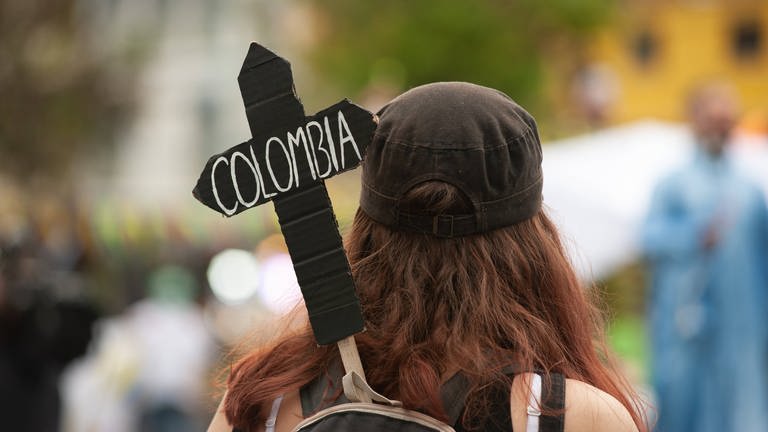 Demonstrantion mit einem Pappkreuz mit der Aufschrift Columbia (Foto: IMAGO, IMAGO / VWPics RF Chepa Beltran)