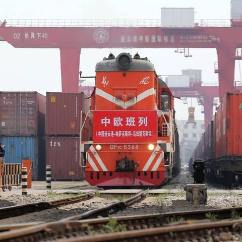 Ein chinesischer Güterzug auf dem Weg nach Europa steht zwischen Containern (Foto: IMAGO, Xinhua)