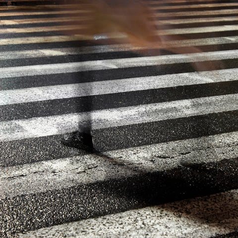 Pedestrian on rainy city street, Rainy city street reflections: One young fragile female disappearing while crossing the wet street in the sparkling night (Foto: IMAGO, Dreamstime)