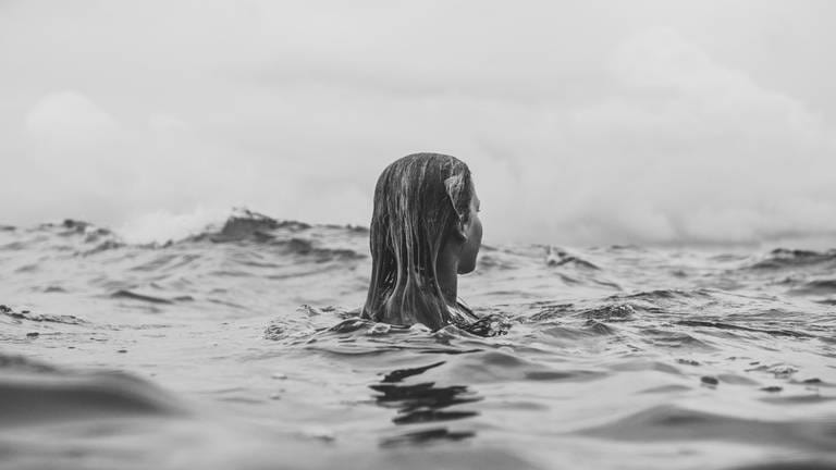 Eine Frau von hinten im Wasser (Foto: Unsplash / Jana Sabeth)
