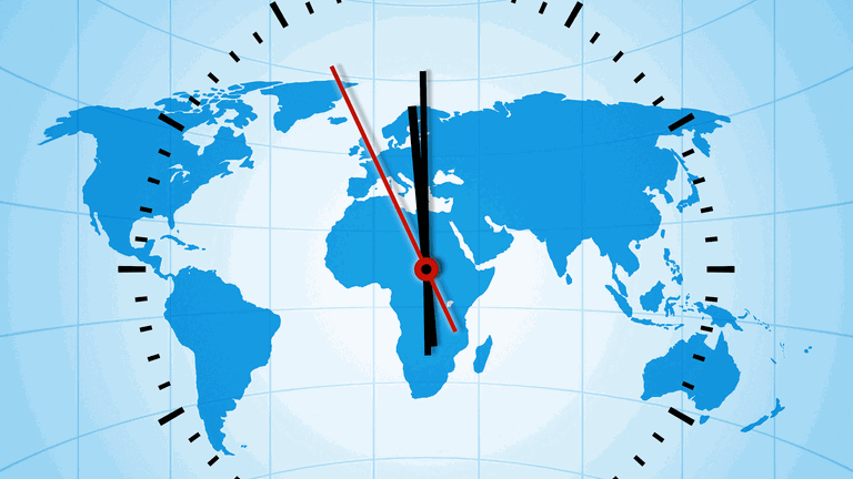 Uhr mit Weltkarte im Hintergrund kurz vor 12 Uhr (Foto: IMAGO, IMAGO/blickwinkel)