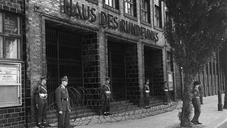 Berlin, 1952 - Der Eingang vor dem Haus des Rundfunks ist mit Stacheldraht abgesperrt, Soldaten der Alliierten stehen davor. (Foto: picture-alliance / Reportdienste, akg-images / Gert Schuetz)