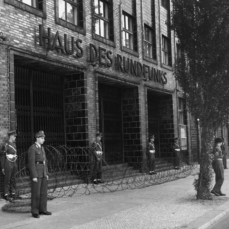 Berlin, 1952 - Der Eingang vor dem Haus des Rundfunks ist mit Stacheldraht abgesperrt, Soldaten der Alliierten stehen davor. (Foto: picture-alliance / Reportdienste, akg-images / Gert Schuetz)