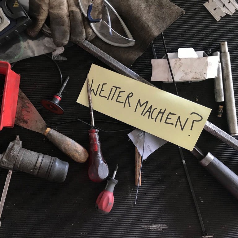 Verschiedene Werkzeuge und Rohrteile und ein Zettel auf dem "Weitermachen? steht (Foto: SWR, Foto: Lisa Spöri)