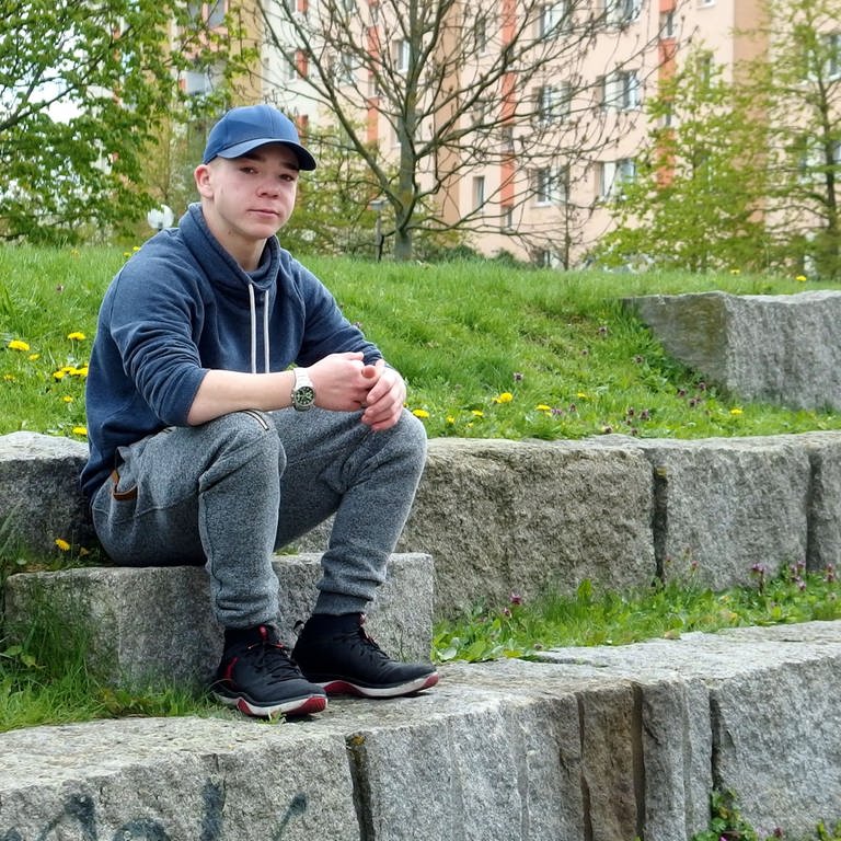 Ein Jugendlicher sitzt auf einer Steintreppe in einer Parkanlage (Foto: Massimo Maio)