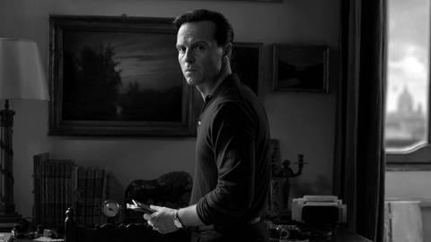 Andrew Scott als Tom Ripley. Er steht in einem Wohnzimmer und blickt konzentriert über die Schulter. (Foto: IMAGO, IMAGO / Landmark Media)
