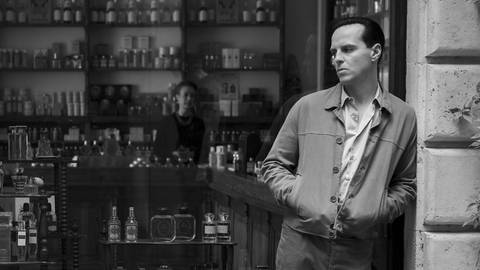 Andrew Scott als Tom Ripley. Er lehnt im Rahmen des Schaufensters einer Bar.