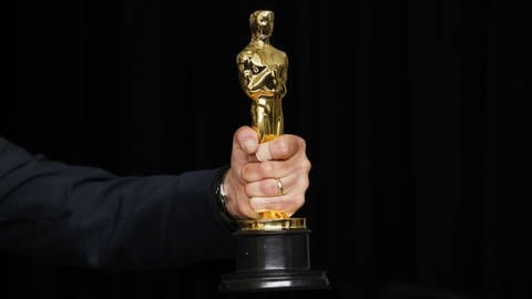 Ein Oscar in einer Hand (Foto: picture-alliance / Reportdienste, picture alliance / newscom)