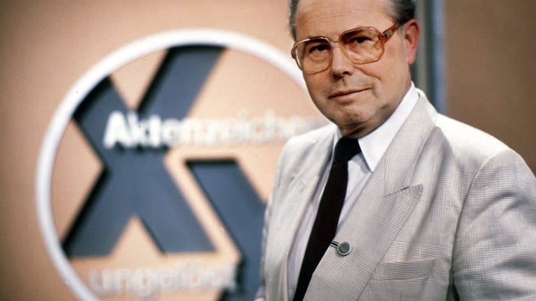 Der Journalist Eduard Zimmermann steht im September 1986 neben dem Logo der von ihm erfundenen, moderierten und produzierten ZDF-Fahndungssendung „Aktenzeichen XY... ungelöst“. 