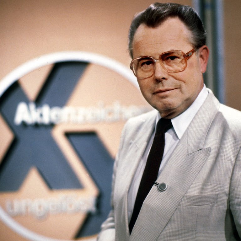 Der Journalist Eduard Zimmermann steht im September 1986 neben dem Logo der von ihm erfundenen, moderierten und produzierten ZDF-Fahndungssendung „Aktenzeichen XY... ungelöst“. 