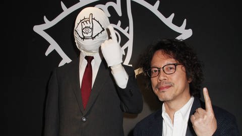 Naoki Urasawa vor der Figur des Freundes aus seinem Manga „20th Century Boys“
