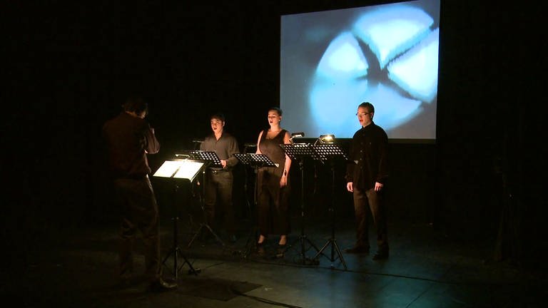 drei Sänger und ein Dirigent vor einer Filmleinwand (Foto: SWR, SWR -)