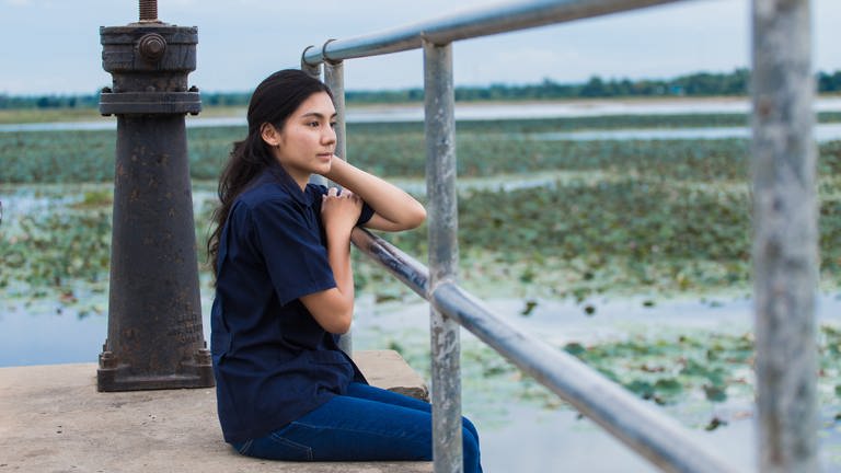 Asian girl sitting on jetty (Foto: IMAGO, Panthermedia)
