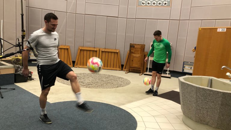 Patrik Weiler vom SV Sinzheim im weißen Trikot und Yannick Seckler vom FC Lichtental im grünen Trikot jonglieren den Ball im Studio