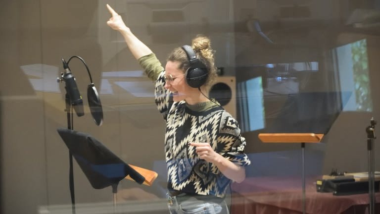 Sarah Grunert mit Arm und Zeigefinger nach oben vor dem Mikrofon stehend