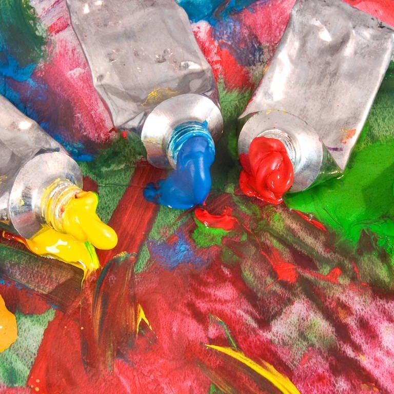 Fünf geöffnete Farbtuben auf buntem Papier (Foto: IMAGO, Design Pics)